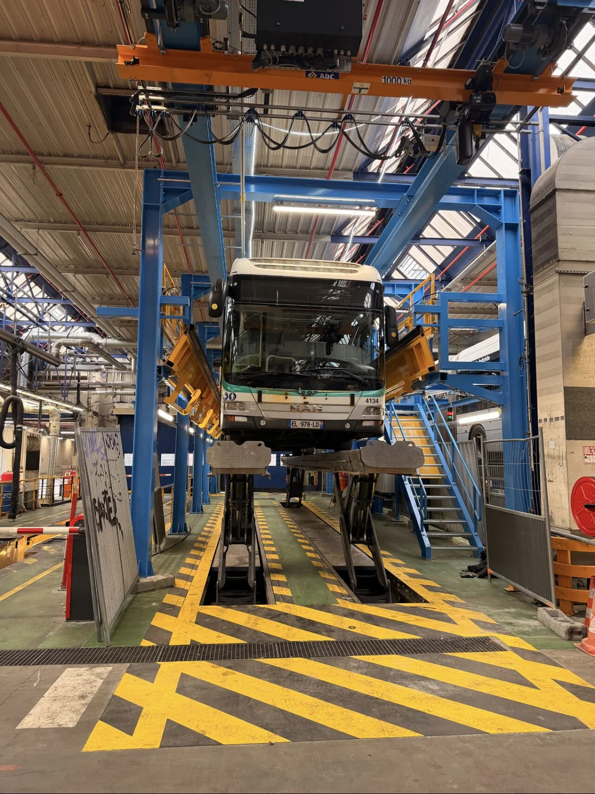 Bus RATP dans une aire de maintenance équipée de passerelles et d’un pont roulant